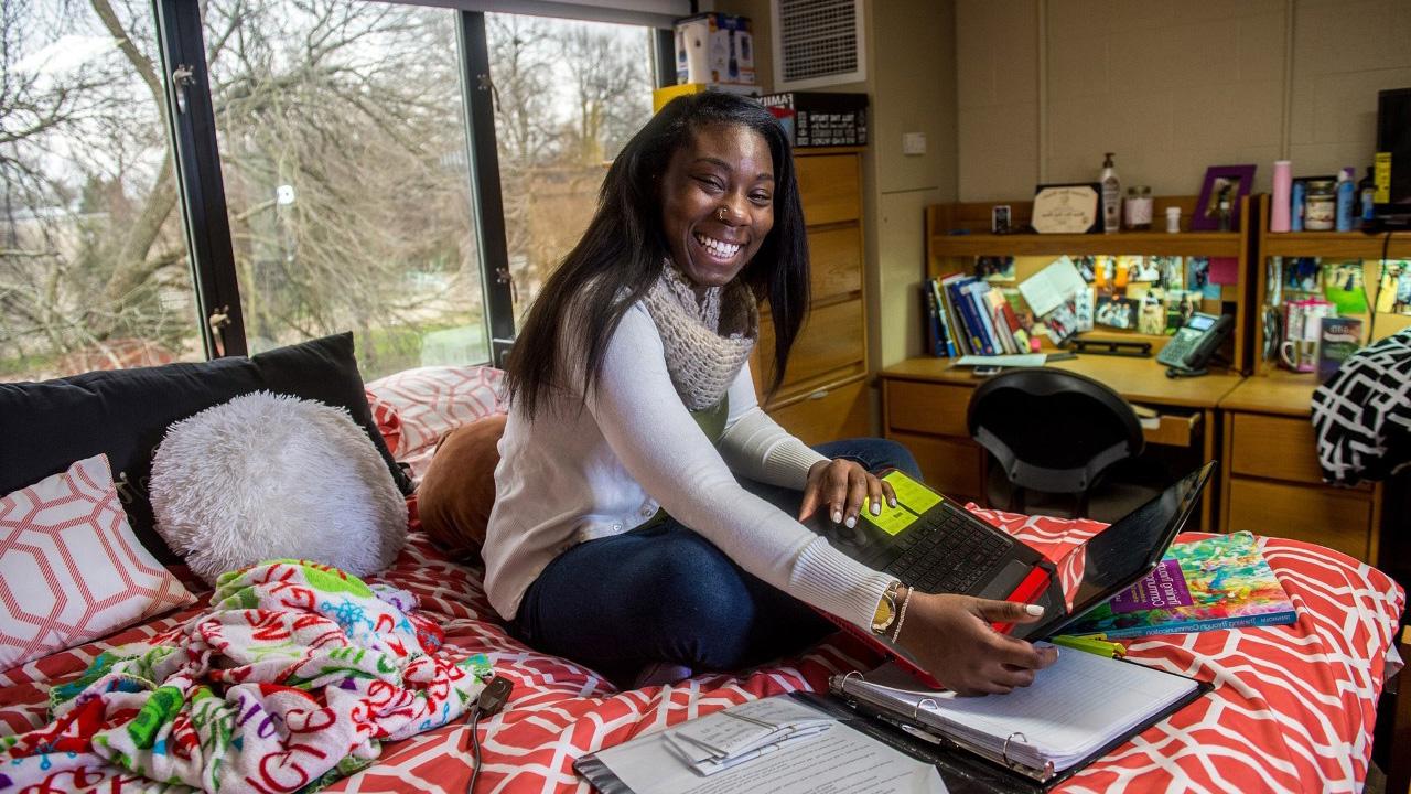 Student on bed in dorm room